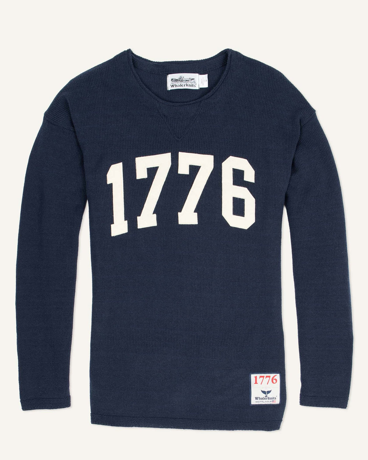 Whalerknits 1776 HOMETOWN Sweater: Navy sweater laid flat with large natural-colored 1776 numerals and a small hem patch. #Color_Navy