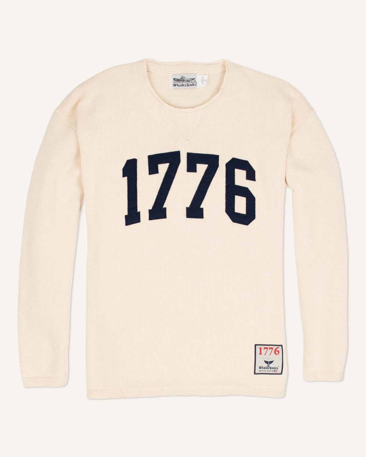 Whalerknits 1776 HOMETOWN Sweater: Natural sweater laid flat with large navy 1776 numerals and a small hem patch. #Color_Natural
