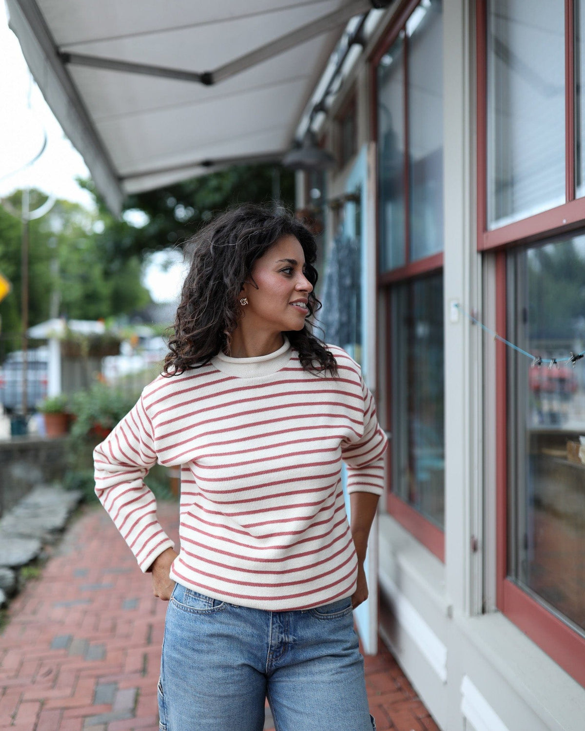 Whalerknits Nantucket Rollneck Sweater: A woman in natural with red stripes and jeans stands outside a shop.