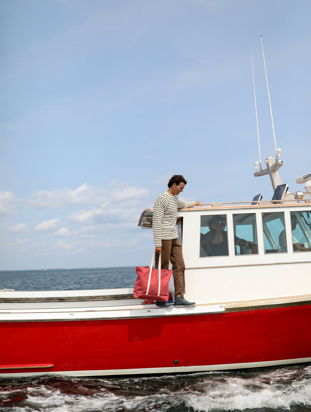A man with a Signal Medium Tote on the side deck of the red lobster boat