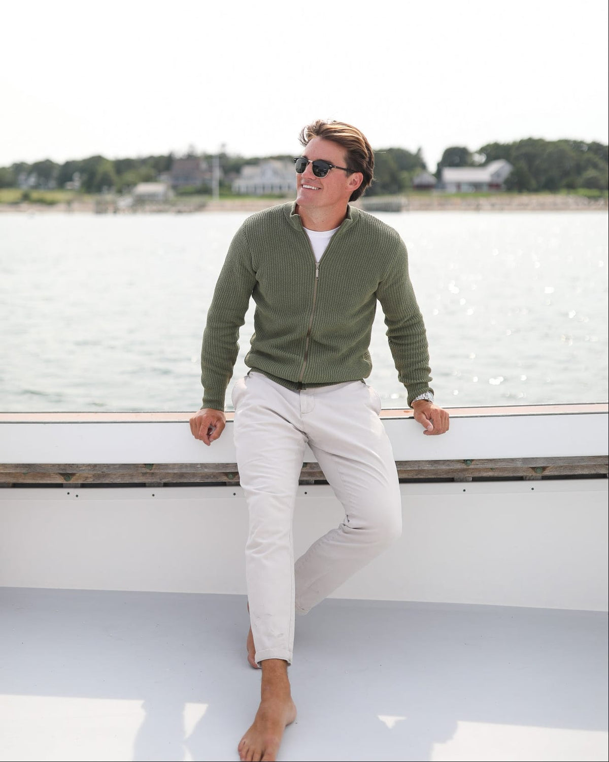Whalerknits Cuttyhunk Full-Zip Cardigan: A barefoot man in olive and white trousers leans against a boat rail.