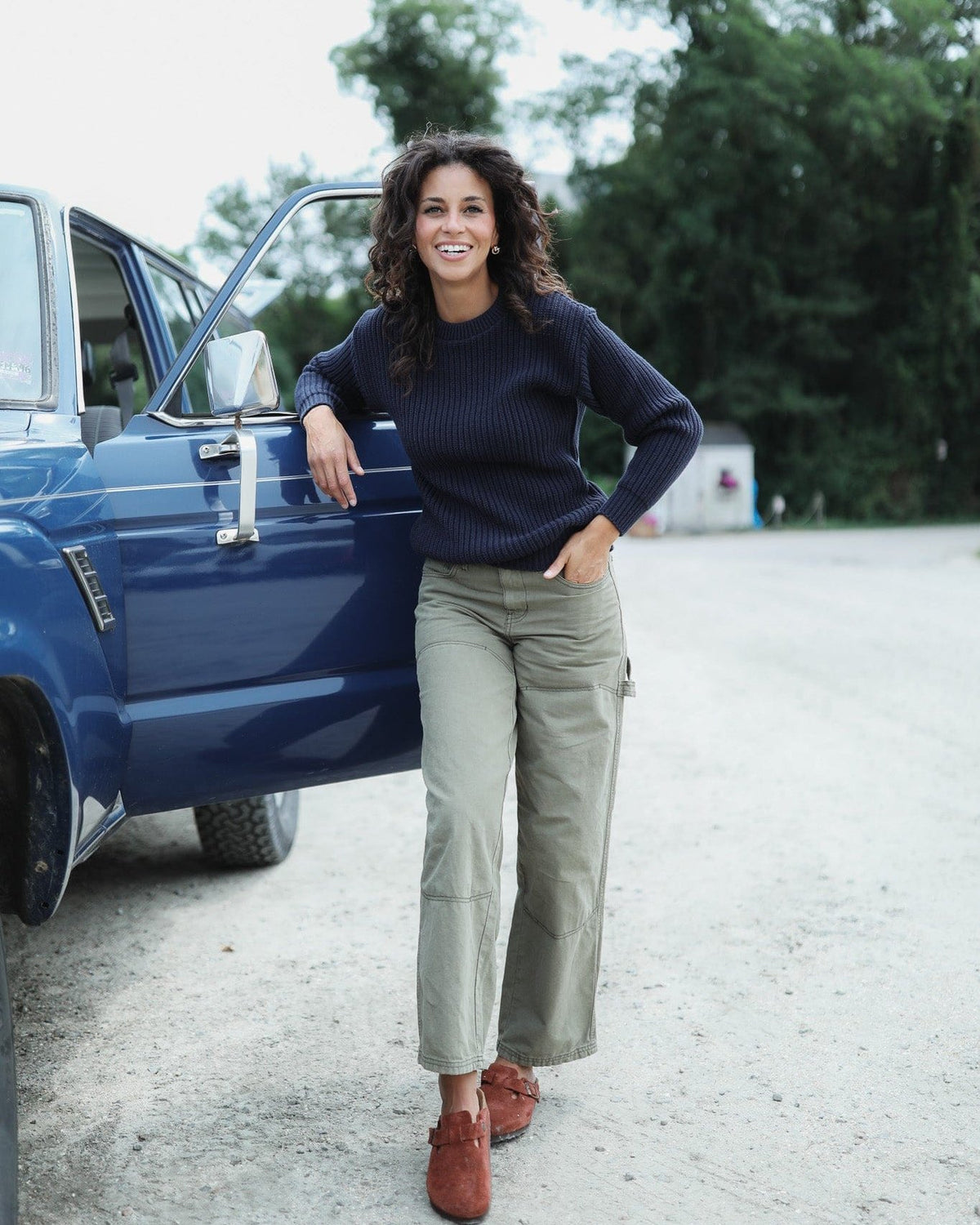 Whalerknits Newport Shaker Knit Crewneck Sweater: A woman wears navy with olive trousers beside an open blue vehicle door.